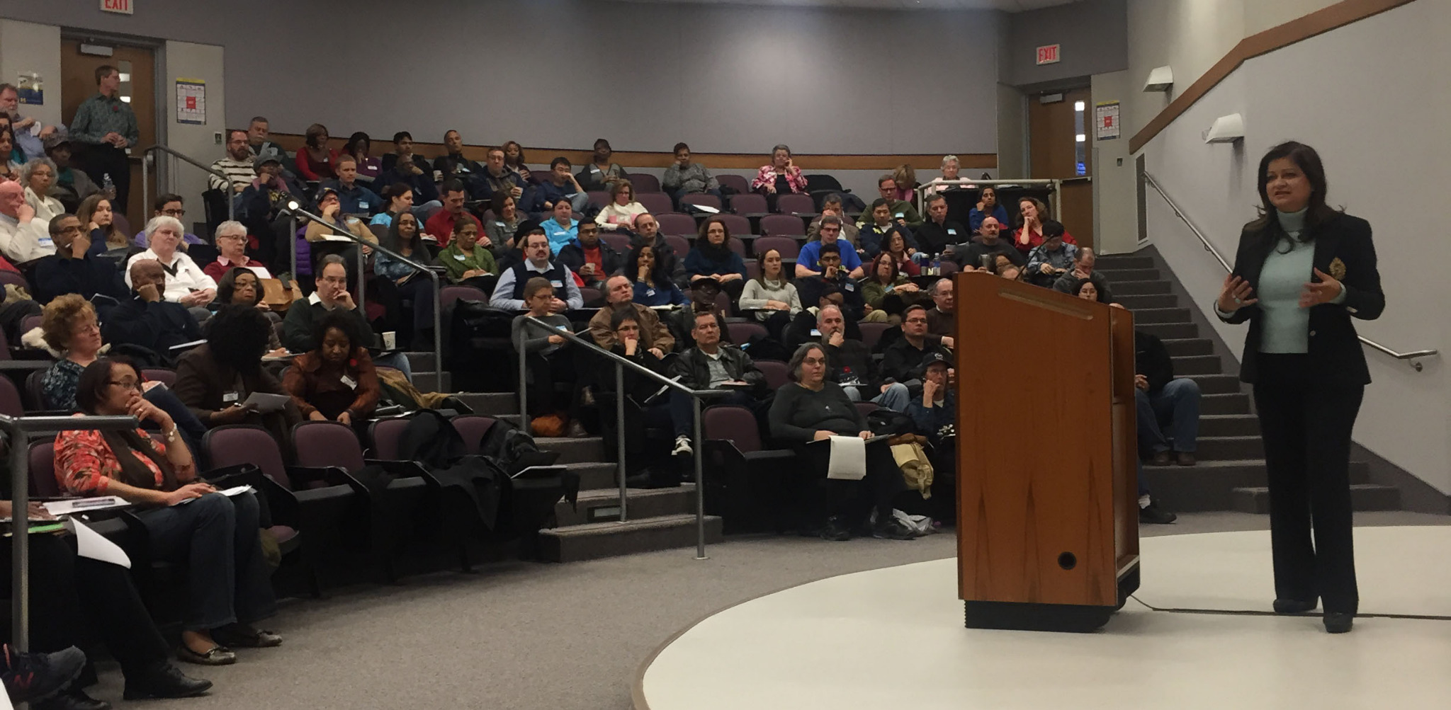 Hena speaking to an audience in an auditorium