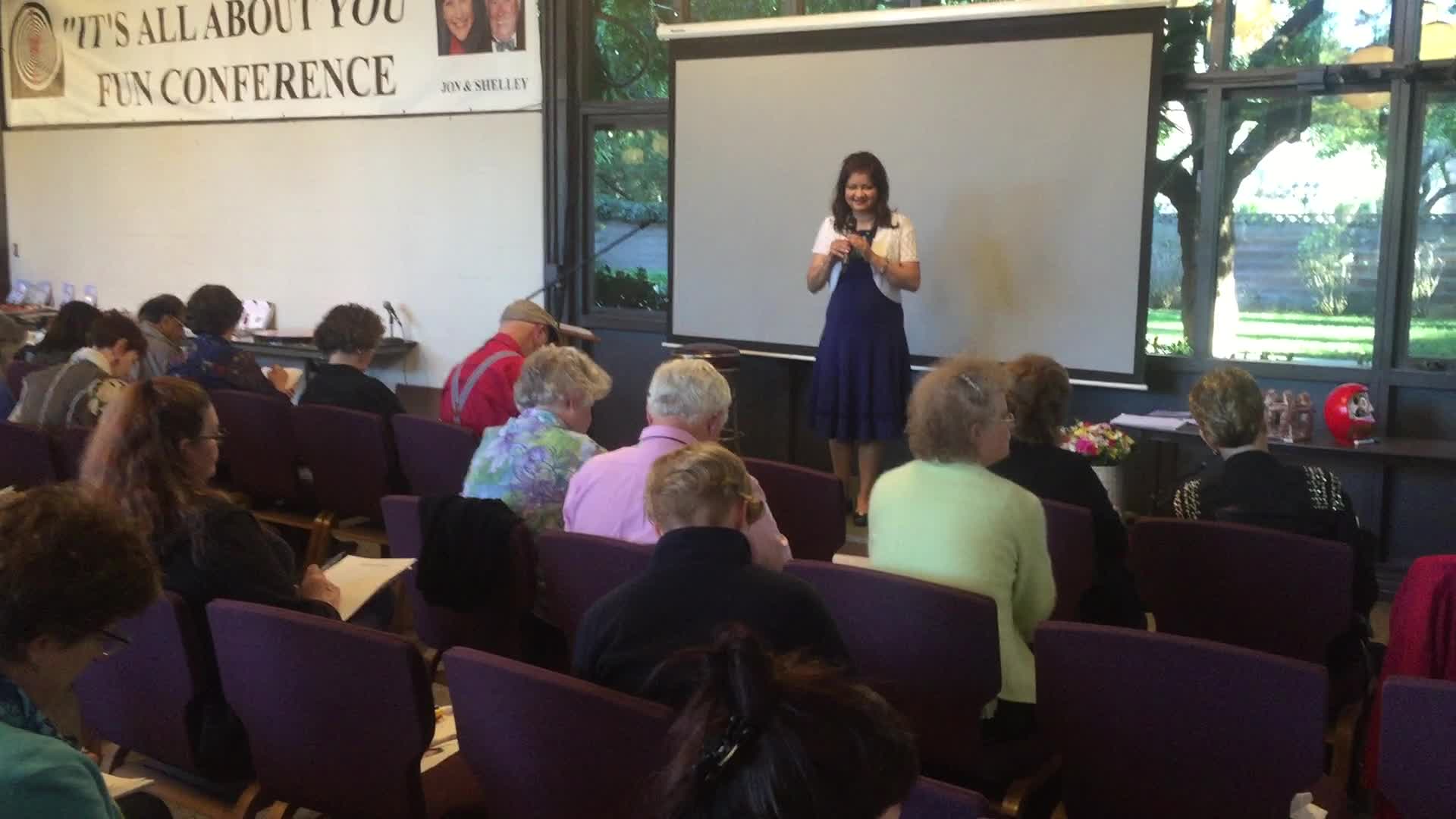 Hena smiling while presenting to a conference audience